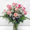 Pink and white roses arranged in a clear glass vase with baby's breath