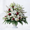 White and red floral arrangement in a white pedestal vase