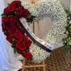 A heart-shaped arrangement combining rich red blooms with soft white baby&rsquo;s breath