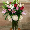 Tall bouquet of pink and red roses with lilies in a glass vase