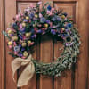 Heart-shaped floral wreath with a burlap bow on a wooden door