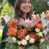 Graduate holding a bouquet of orange and white flowers