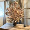 Dried wildflower arrangement in a dark vase on a wooden table