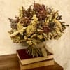 Dried flower bouquet tied with burlap ribbon, resting on stacked books
