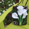White calla lilies arranged on a brown tote bag sitting on a lime-green chair.