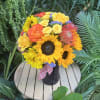 Bouquet of sunflowers and yellow-orange roses in a dark vase