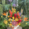 Tropical bouquet with bird of paradise, roses, and purple allium in a white vase
