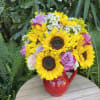 Bouquet of sunflowers and roses in a red pitcher vase