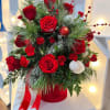 Red and white roses arranged with pine and berries in a red hatbox
