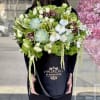 Large bouquet of white orchids, succulents, and green blooms in a black box