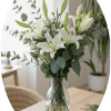 Pure white lilies rise gracefully in a clear glass vase, a calm