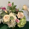 Peach and blush roses mingle with pink lisianthus and a single purple