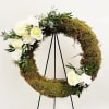 Moss wreath with white roses and thistle on a black stand