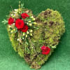 Heart-shaped moss arrangement with red roses and small white flowers
