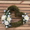 White rose floral wreath with moss on a wooden slat background