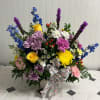 Colorful mixed flower arrangement in a white basket with a floral ribbon