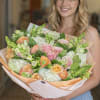 A lush hand-tied bouquet in a soft pastel palette of pink, peach