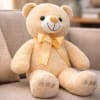 Plush teddy bear with a satin bow sitting on a sofa