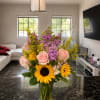 Bright yellow sunflowers pair with soft pink roses and tall purple filler
