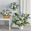 Blue and white floral arrangements in white and wooden containers