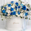 Blue and white rose arrangement in a round white box with ribbon