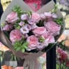 Bouquet of pink roses and pale pink lisianthus wrapped in taupe paper