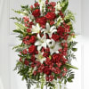 Standing spray of red roses, white lilies, and mixed red and white flowers on an easel.