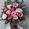 Pink roses and gerbera daisies in a purple glass vase