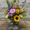 Mixed bouquet in a glass vase with sunflowers, gerberas, and snapdragons