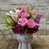 Pink roses and lilies arranged in a white ceramic vase