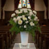 White floral arrangement in a tall glass vase on a pedestal