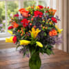 A bright, garden-fresh burst of orange roses and sunny yellow lilies that