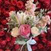 Pink and white bouquet in a glass vase with a white ribbon