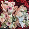 Two pastel bouquets with roses, gerbera daisies, and carnations against a red rose wall