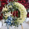 Heart-shaped floral wreath with white flowers, blue accents, and a blue ribbon