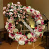 Large pink and white floral wreath on an easel with a memorial ribbon
