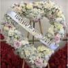 Heart-shaped floral wreath with white and pink roses on an easel