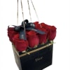 Red roses arranged in a black Dior gift bag with ribbon handles