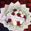 Bouquet of red, white, and blush roses with baby's breath and a pink ribbon