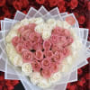 Heart-shaped bouquet of pink and white roses wrapped in translucent paper