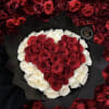 Heart-shaped bouquet of red and white roses wrapped in black paper