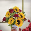 Sunflowers and red roses arranged in a decorative boot vase