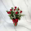 Red roses in a glass vase with baby's breath and a red ribbon
