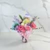 Colorful bouquet in a glass vase with a small festive doll topper