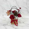 Red roses in a gift bag with a pinecone and holiday decorations