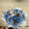 Blue rose bouquet with a small snowman ornament and pinecones