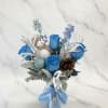 Blue rose bouquet with a snowman ornament and ribbon in a vase
