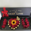 Gift box with red roses, a sunflower, and chocolates arranged in the shape of "I LOVE U"