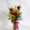 Red roses and yellow sunflowers in a glass vase with a red ribbon