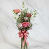 Pink and white rose bouquet in a clear glass vase with a pink ribbon